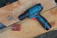 Un grande cacciavite e un insieme dei pezzi in arancia accanto ad un mucchio delle viti sui bordi di legno marroni fotografie stock libere da diritti Un grande cacciavite e un insieme dei pezzi in arancia accanto ad un mucchio delle viti sui bordi di legno marroni fotografie stock libere da diritti