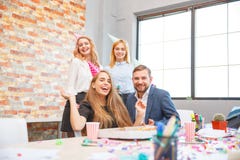 Un groupe des hommes et de femmes travaillant dans le bureau, mangeant de la pizza dans une humeur de fête photo stock Un groupe des hommes et de femmes travaillant dans le bureau, mangeant de la pizza dans une humeur de fête photo stock