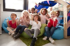 Un groupe multi-ethnique d'écoliers infantiles s'asseyant sur des fauteuils poire dans un coin confortable du t de salle de class photo libre de droits Un groupe multi-ethnique d'écoliers infantiles s'asseyant sur des fauteuils poire dans un coin confortable du t de salle de class photo libre de droits