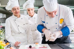 Un grupo de cocineros jovenes prepairing la comida en restaurante de lujo foto de archivo libre de regalías Un grupo de cocineros jovenes prepairing la comida en restaurante de lujo foto de archivo libre de regalías