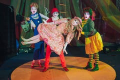 Un gruppo di pagliacci, un uomo del pagliaccio alzato nelle sue armi una donna che ritrae una bambola fissa immagine stock Un gruppo di pagliacci, un uomo del pagliaccio alzato nelle sue armi una donna che ritrae una bambola fissa immagine stock