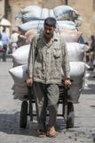 Un hombre acarrea una carga pesada de sacos a través bazar del ili de Khan el Khal ' en El Cairo, Egipto imágenes de archivo libres de regalías Un hombre acarrea una carga pesada de sacos a través bazar del ili de Khan el Khal ' en El Cairo, Egipto imágenes de archivo libres de regalías