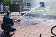 Un hombre del ` s del bombero está enseñando a un niño, muchacha a apagar un fuego tirando una corriente del agua de un bronzboyt fotografía de archivo libre de regalías Un hombre del ` s del bombero está enseñando a un niño, muchacha a apagar un fuego tirando una corriente del agua de un bronzboyt fotografía de archivo libre de regalías