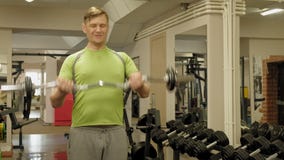 Un hombre gordo levanta un barbell del ez mientras que se coloca en el gimnasio Ejercicio para el b?ceps Aptitud Forma de vida sa metrajes Un hombre gordo levanta un barbell del ez mientras que se coloca en el gimnasio Ejercicio para el b?ceps Aptitud Forma de vida sa metrajes