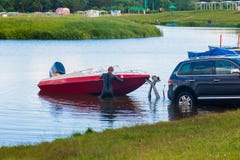 Un hombre saca de un barco el lago Lanzamiento del barco La máquina saca del barco el agua Pesca en el barco imagen de archivo Un hombre saca de un barco el lago Lanzamiento del barco La máquina saca del barco el agua Pesca en el barco imagen de archivo