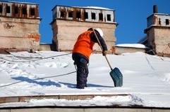 Un homme avec une pelle enlève la neige d'un toit images stock Un homme avec une pelle enlève la neige d'un toit images stock