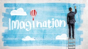Un homme d'affaires dessine le ciel bleu derrière une imagination de mot avec un ballon à air chaud au lieu d'un point au-dessus Image stock Un homme d'affaires dessine le ciel bleu derrière une imagination de mot avec un ballon à air chaud au lieu d'un point au-dessus Image stock