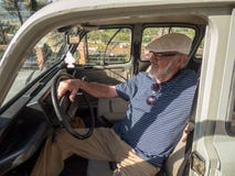 Un homme de sourire plus âgé s'asseyant dans sa voiture dans le jour ensoleillé images stock Un homme de sourire plus âgé s'asseyant dans sa voiture dans le jour ensoleillé images stock