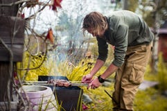 Un homme fait frire des chiches-kebabs sur Mongal dans son complot de jardin images stock Un homme fait frire des chiches-kebabs sur Mongal dans son complot de jardin images stock