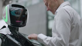 Un homme se tient avec un bot de robot et lui pose des questions et demande l'aide en cliquant sur sur l'écran sur le corps de ro clips vidéos Un homme se tient avec un bot de robot et lui pose des questions et demande l'aide en cliquant sur sur l'écran sur le corps de ro clips vidéos