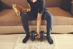 Un homme va chercher dedans des sports ? la maison avec des halt?res avec un chat photo libre de droits Un homme va chercher dedans des sports ? la maison avec des halt?res avec un chat photo libre de droits