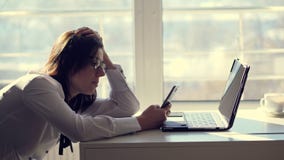 Un jeune employé de bureau féminin de commis passe en revue les réseaux sociaux à un téléphone portable, pendant son jour de trav Un jeune employé de bureau féminin de commis passe en revue les réseaux sociaux à un téléphone portable, pendant son jour de trav
