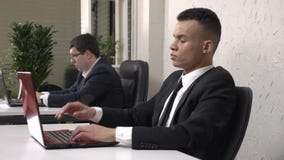 Un jeune homme d'affaires masculin africain réussi travaillant dans le bureau sur un ordinateur portable, fatigué, tenant sa tête banque de vidéos Un jeune homme d'affaires masculin africain réussi travaillant dans le bureau sur un ordinateur portable, fatigué, tenant sa tête banque de vidéos