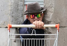 Un jeune homme en chapeau et verres avec la vente d'inscription s'élève par le mur en béton cassé Un homme tient un panier de image stock Un jeune homme en chapeau et verres avec la vente d'inscription s'élève par le mur en béton cassé Un homme tient un panier de image stock