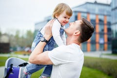 Un jeune papa repose une petite fille dans une chaise avant de monter une bicyclette photos libres de droits Un jeune papa repose une petite fille dans une chaise avant de monter une bicyclette photos libres de droits