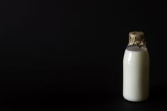 Un lait de bouteille sur un fond noir photos stock Un lait de bouteille sur un fond noir photos stock