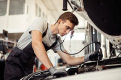 Un mecánico joven pero calificado está conduciendo un examen detallado de un coche foto de archivo libre de regalías Un mecánico joven pero calificado está conduciendo un examen detallado de un coche foto de archivo libre de regalías