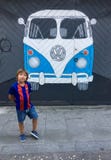 Un muchacho en la forma de una Barcelona FC cerca de una pintura de la pintada de un autobús de Volkswagen pintó en una pared imagen de archivo Un muchacho en la forma de una Barcelona FC cerca de una pintura de la pintada de un autobús de Volkswagen pintó en una pared imagen de archivo