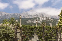 Un mur avec les tourelles mauresques, envahies avec la verdure luxuriante et une vue des crêtes d'AI-Pétri dans les nuages image stock Un mur avec les tourelles mauresques, envahies avec la verdure luxuriante et une vue des crêtes d'AI-Pétri dans les nuages image stock