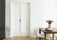 Un mur blanc avec la porte à deux battants à côté d'une table de petit déjeuner en bois et chaises dans un intérieur de salle à m photos stock Un mur blanc avec la porte à deux battants à côté d'une table de petit déjeuner en bois et chaises dans un intérieur de salle à m photos stock