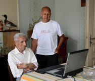 Un más viejo hombre 88 años de trabajos sobre un ordenador portátil y un hombre más joven 60 años lo comprueba fotografía de archivo Un más viejo hombre 88 años de trabajos sobre un ordenador portátil y un hombre más joven 60 años lo comprueba fotografía de archivo