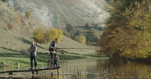 Un niño pequeño con dos individuos que pescan en un lago en la naturaleza metrajes Un niño pequeño con dos individuos que pescan en un lago en la naturaleza metrajes