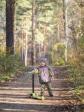 Un niño pequeño se coloca con una vespa en el parque fotografía de archivo Un niño pequeño se coloca con una vespa en el parque fotografía de archivo