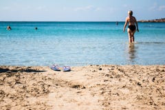 Un non identifié et hors de la femme de foyer entre dans l'eau laissant ses sandales photographie stock libre de droits Un non identifié et hors de la femme de foyer entre dans l'eau laissant ses sandales photographie stock libre de droits