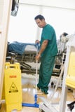Un'ordinanza che pass lo straccioare sul pavimento in un quartiere di ospedale fotografia stock Un'ordinanza che pass lo straccioare sul pavimento in un quartiere di ospedale fotografia stock