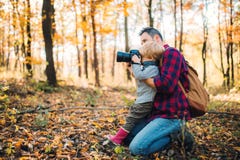 Un padre maturo e un figlio del bambino in una foresta di autunno, prendente le immagini con una macchina fotografica immagine stock Un padre maturo e un figlio del bambino in una foresta di autunno, prendente le immagini con una macchina fotografica immagine stock