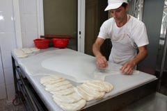 Un panettiere impasta la pasta per la torta del formaggio con il rullo e la farina in forno nella città †di Sofia, Bulgaria “4 Immagine Stock Un panettiere impasta la pasta per la torta del formaggio con il rullo e la farina in forno nella città †di Sofia, Bulgaria “4 Immagine Stock