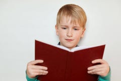 Un pequeño muchacho bonito con el pelo rubio y los ojos azules que llevaban a cabo rojo abrió historias interesantes de lectura d fotos de archivo libres de regalías Un pequeño muchacho bonito con el pelo rubio y los ojos azules que llevaban a cabo rojo abrió historias interesantes de lectura d fotos de archivo libres de regalías