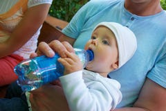 Un pequeño niño sienta y bebe el agua fotografía de archivo libre de regalías Un pequeño niño sienta y bebe el agua fotografía de archivo libre de regalías