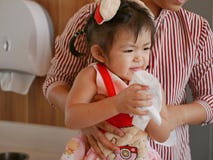 Un petit bébé asiatique, avec l'aide de sa mère, apprenant à essuyer ses mains après lavage de elles image stock Un petit bébé asiatique, avec l'aide de sa mère, apprenant à essuyer ses mains après lavage de elles image stock