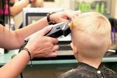Un petit garçon coupe un coiffeur dans le salon L'enfant observe une bande dessinée Écran vert sur un ordinateur portable pour la photo stock Un petit garçon coupe un coiffeur dans le salon L'enfant observe une bande dessinée Écran vert sur un ordinateur portable pour la photo stock