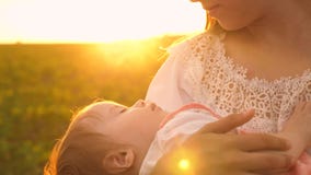Un piccolo bambino dorme nelle armi di sua madre, al tramonto, fucilazione lenta fotografia stock Un piccolo bambino dorme nelle armi di sua madre, al tramonto, fucilazione lenta fotografia stock