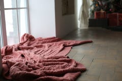 Un plaid brun tricoté se trouve près de la fenêtre Image libre de droits Un plaid brun tricoté se trouve près de la fenêtre Image libre de droits