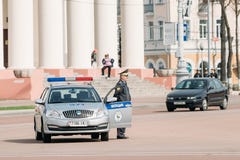Un policier se tient à côté d'une voiture de patrouille à l'arrière-plan Dramat Photos libres de droits Un policier se tient à côté d'une voiture de patrouille à l'arrière-plan Dramat Photos libres de droits