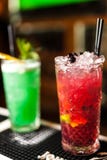 Un primo piano di due cocktail rossi e verdi variopinti con calce e zucchero bruno nella barra, fondo vago fotografia stock Un primo piano di due cocktail rossi e verdi variopinti con calce e zucchero bruno nella barra, fondo vago fotografia stock