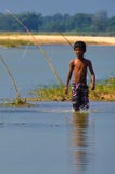 Un ragazzo stava camminando nell'acqua bassa di un fiume dopo avere fuso le sue canne da pesca fotografia stock Un ragazzo stava camminando nell'acqua bassa di un fiume dopo avere fuso le sue canne da pesca fotografia stock