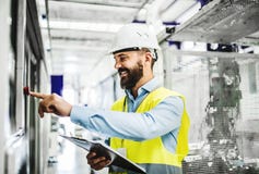 Un ritratto di un ingegnere industriale dell'uomo con la lavagna per appunti in una fabbrica, lavorante immagine stock Un ritratto di un ingegnere industriale dell'uomo con la lavagna per appunti in una fabbrica, lavorante immagine stock