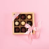 Un sistema de diversos chocolates en una caja de papel con una cinta de satén en un fondo brillante Disposición plana Concepto fe foto de archivo Un sistema de diversos chocolates en una caja de papel con una cinta de satén en un fondo brillante Disposición plana Concepto fe foto de archivo