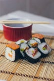 Un sushi fijó con los palillos del cuenco y del bambú de la salsa en el fondo de bambú Imagen de archivo libre de regalías Un sushi fijó con los palillos del cuenco y del bambú de la salsa en el fondo de bambú Imagen de archivo libre de regalías