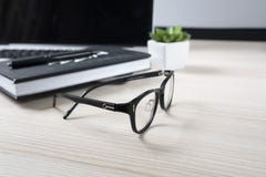 Un taccuino chiuso su un computer portatile, sui vetri e su un fiore verde fotografia stock libera da diritti Un taccuino chiuso su un computer portatile, sui vetri e su un fiore verde fotografia stock libera da diritti