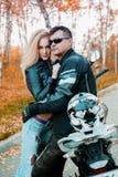Un tipo attraente e una giovane donna in un'attrezzatura di cuoio nera con un motociclo fotografia stock libera da diritti Un tipo attraente e una giovane donna in un'attrezzatura di cuoio nera con un motociclo fotografia stock libera da diritti