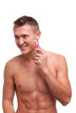 Un tipo con un fronte felice rade le sue guance con un rasoio rosa su un fondo isolato bianco immagini stock libere da diritti Un tipo con un fronte felice rade le sue guance con un rasoio rosa su un fondo isolato bianco immagini stock libere da diritti