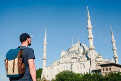 Un uomo in un berretto da baseball con uno zaino accanto alla moschea blu è una vista famosa a Costantinopoli Viaggio, turismo immagini stock Un uomo in un berretto da baseball con uno zaino accanto alla moschea blu è una vista famosa a Costantinopoli Viaggio, turismo immagini stock