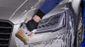 Un uomo lava i fari dell'automobile Concetto di autolavaggio manuale stock footage Un uomo lava i fari dell'automobile Concetto di autolavaggio manuale stock footage