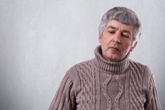 Un uomo senior triste che sembra il basso premuroso si è vestito in maglione Un uomo anziano wrinlked con capelli grigi che pensa Immagini Stock Un uomo senior triste che sembra il basso premuroso si è vestito in maglione Un uomo anziano wrinlked con capelli grigi che pensa Immagini Stock