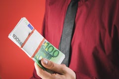 un uomo in una camicia rossa con una carta tiene in sua mano un batuffolo delle fatture su un fondo rosso immagini stock un uomo in una camicia rossa con una carta tiene in sua mano un batuffolo delle fatture su un fondo rosso immagini stock